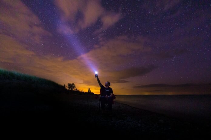 Photo by Venrick Azcueta a man holding a flashlight up in the air