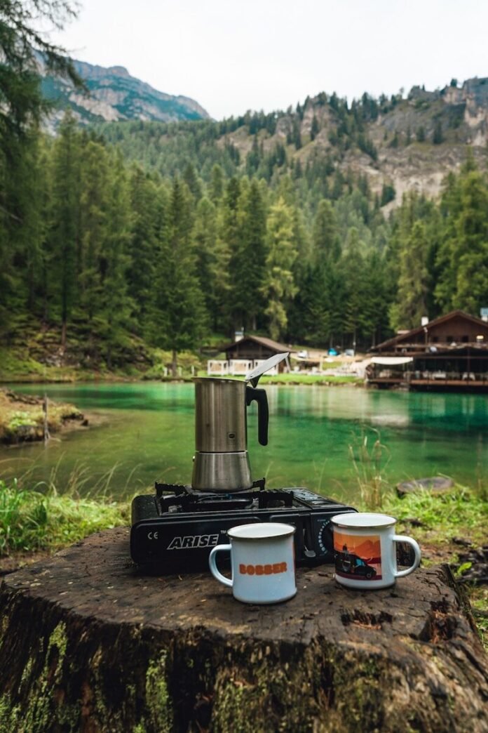 Photo by Erik Fabian Coffee brewing by a serene mountain lake