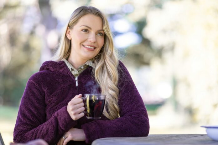 Photo by Rydale Clothing A woman sitting at a table with a cup of coffee
