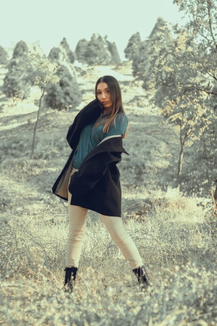 Photo by Navid Sohrabi a woman standing in a field with trees in the background