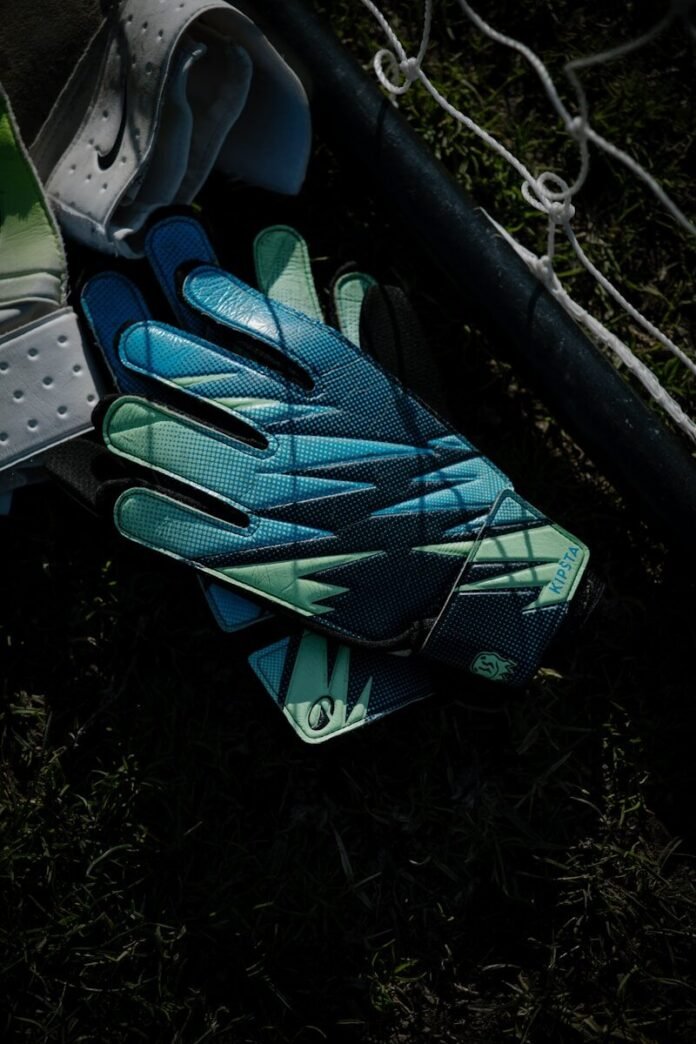 Photo by soonita omar Goalkeeper gloves resting on grass near a net.